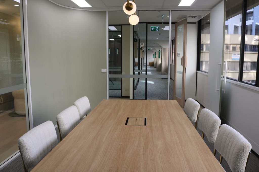 Modern conference room with wooden table and upholstered chairs, showcasing commercial interior design for office fit-out in Canberra City.