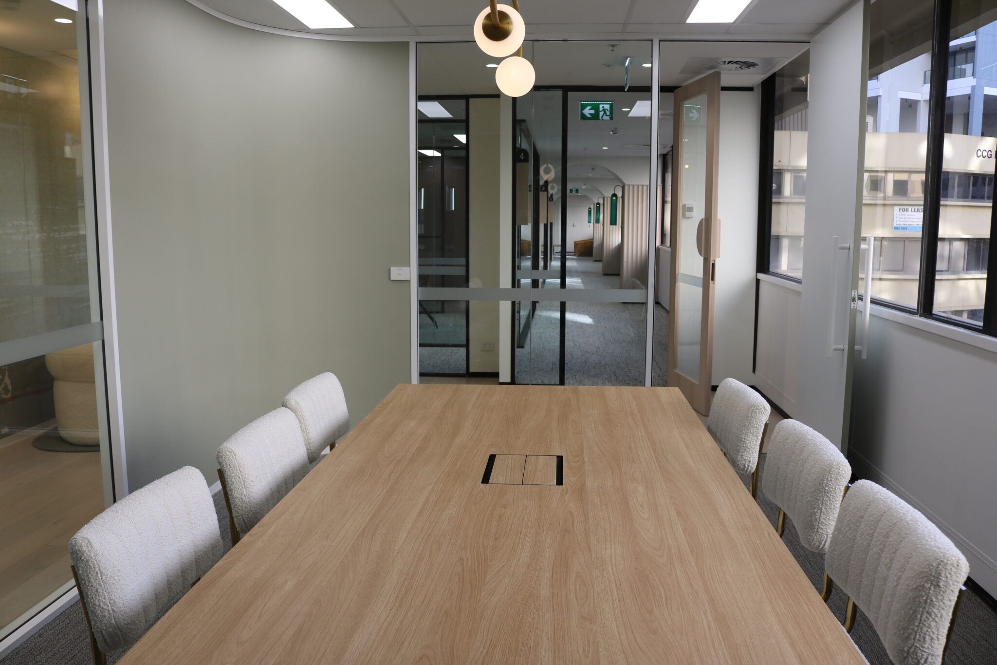 Modern conference room with wooden table and upholstered chairs, showcasing a professional office fitout in Canberra City, highlighting quality finishes and design elements.
