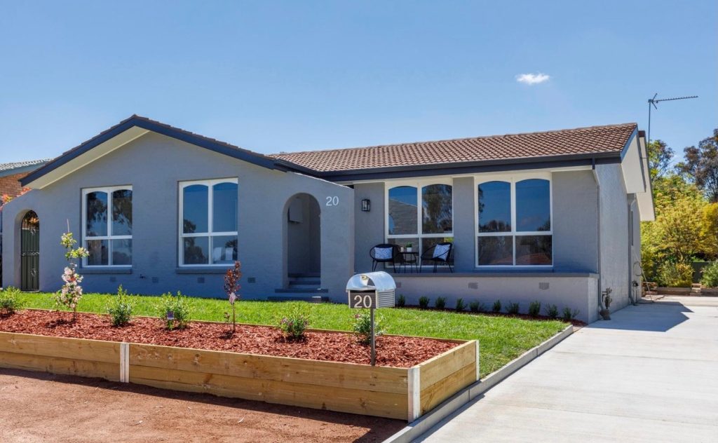 Exterior view of a freshly painted home with modern design, featuring a grey facade, landscaped garden, and a house number sign, showcasing C&C Painting Group's home repainting services.