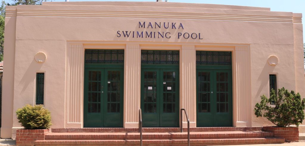 Manuka Swimming Pool exterior with green doors and windows, showcasing recent commercial repaint by C&C Painting Group.