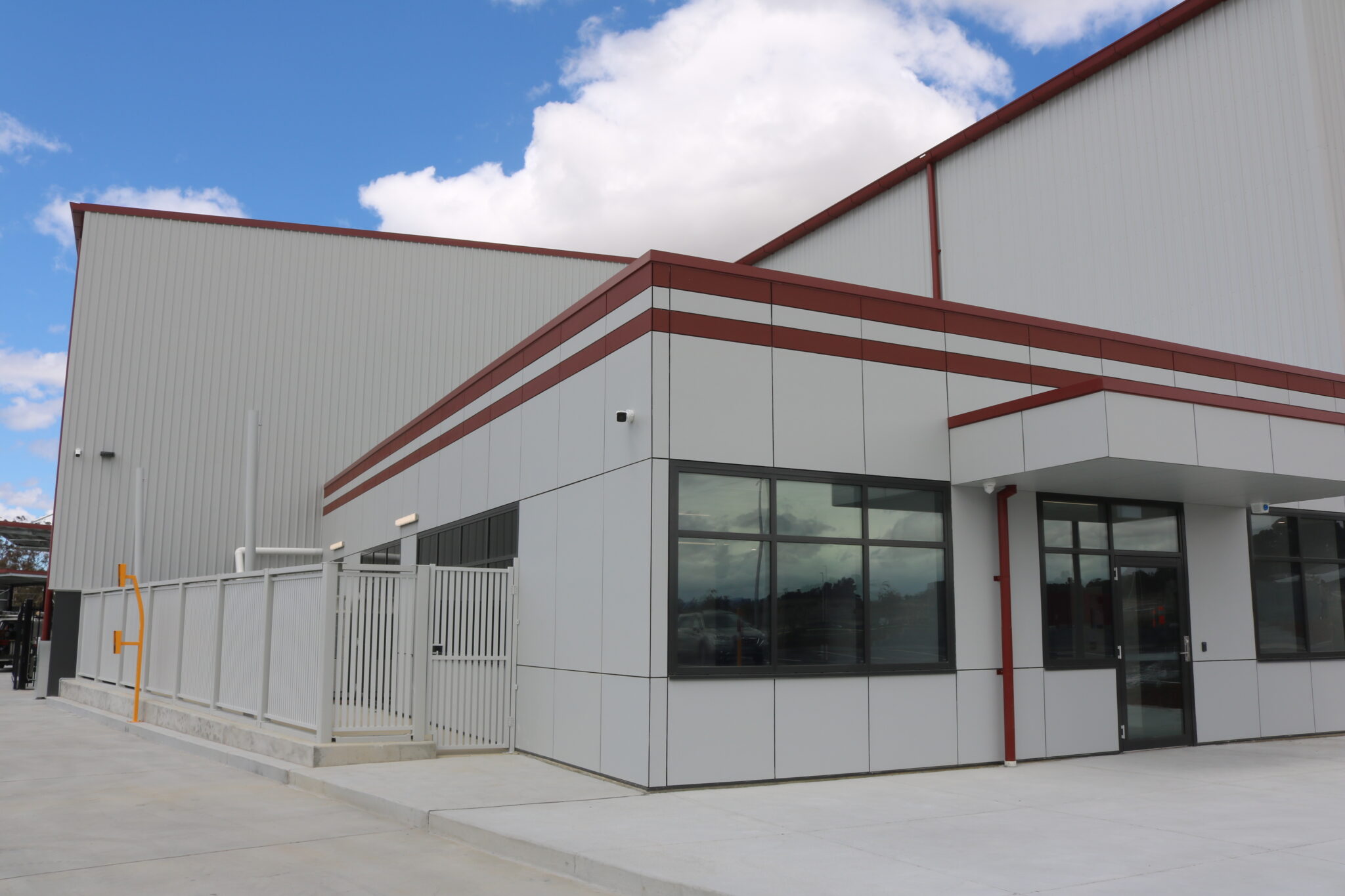 Modern commercial building exterior with grey and red cladding, large windows, and a gated entrance, representing C&C Painting Group's quality painting services in Hume.