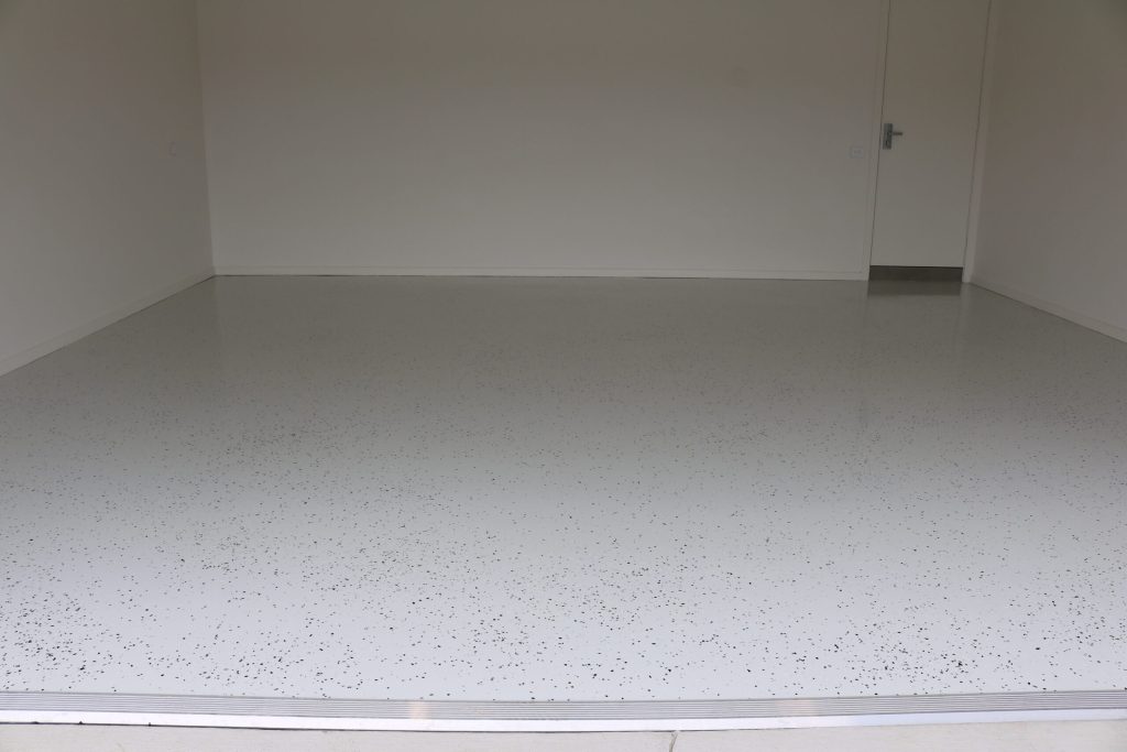 Decorative concrete garage floor resurfacing showcasing a smooth, white surface with black speckles, highlighting C&C Painting Group's expertise in home improvement.