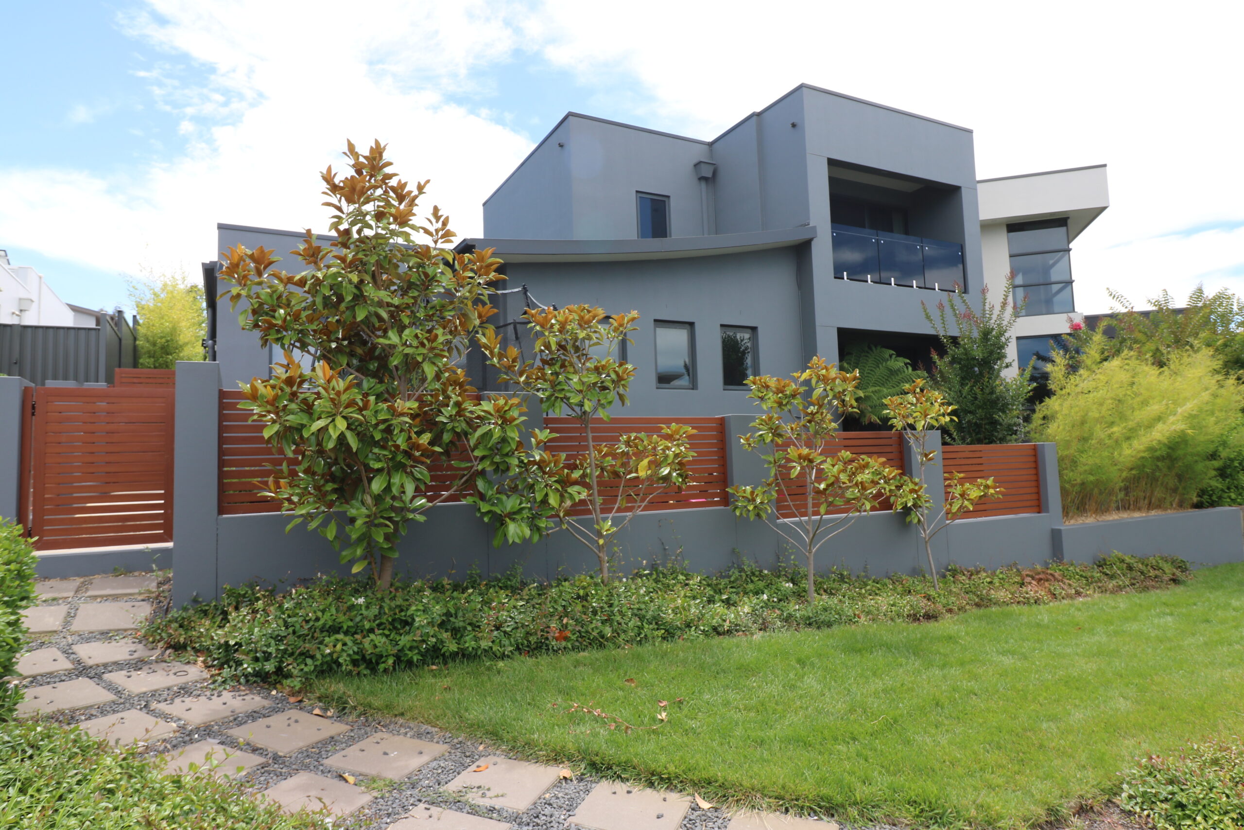 Modern grey exterior home in Forde, Canberra, featuring landscaped garden, wooden fence, and pathway, showcasing C&C Painting Group's exterior repaint services.