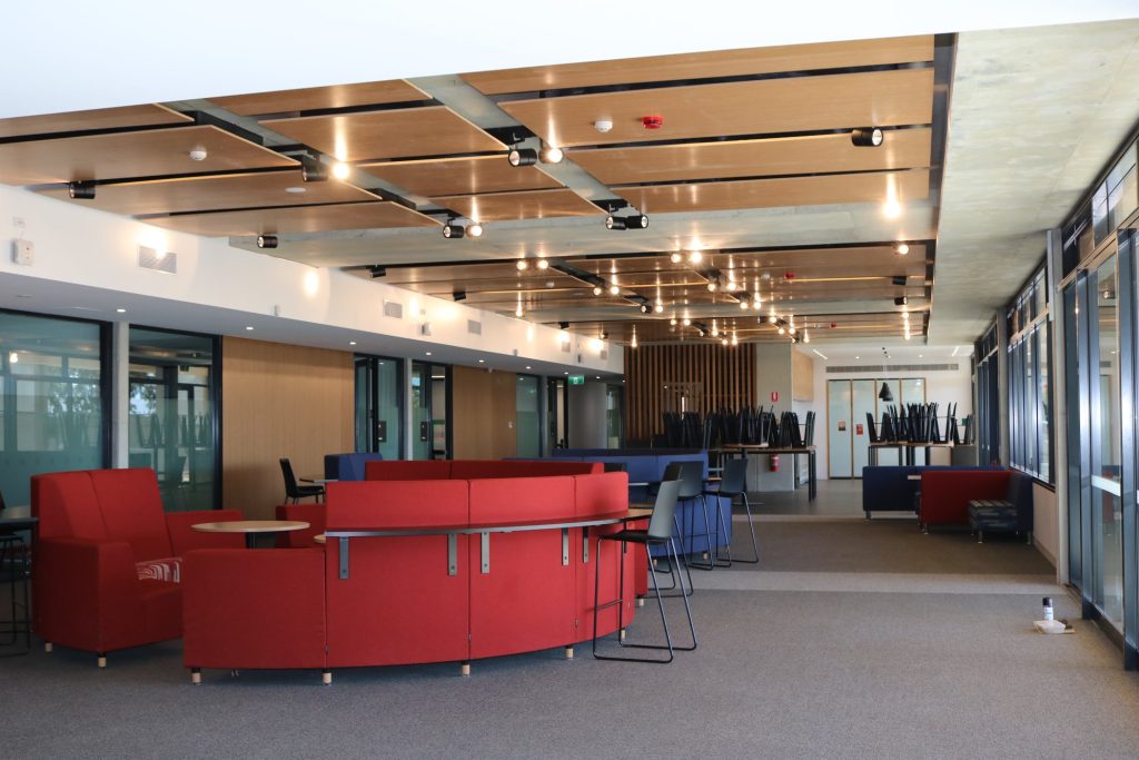 Interior view of a modern commercial space featuring red and blue seating arrangements, large windows, and contemporary lighting, showcasing the interior design work by C&C Painting Group for commercial projects in Canberra.