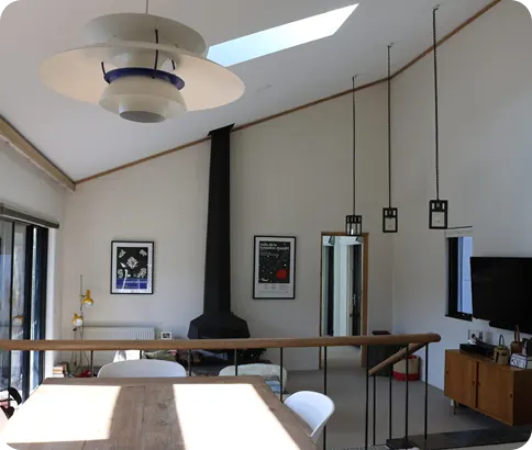 Modern interior of a Canberra home featuring a dining area with a wooden table, a sleek pendant light, and a black fireplace, showcasing a stylish and inviting atmosphere ideal for professional repainting services.