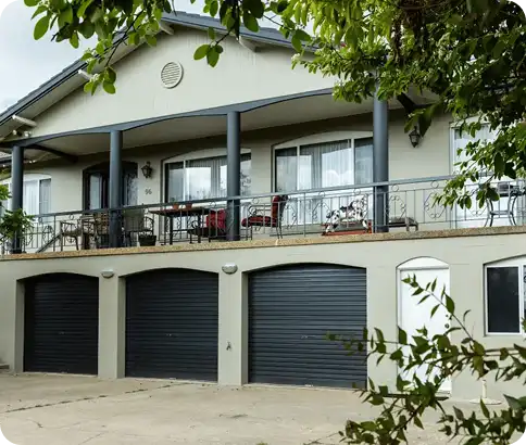 Residential home exterior with a covered porch, decorative railings, and three garage doors, showcasing a well-maintained property in Canberra, emphasising the quality of C&C Painting Group's repainting services.
