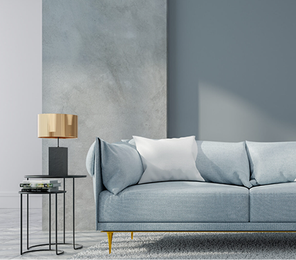 Modern living room featuring a light blue sofa, decorative white pillow, sleek side table with a gold lamp, and a textured gray wall, illustrating C&C Painting Group's commitment to stylish and lasting interior transformations.