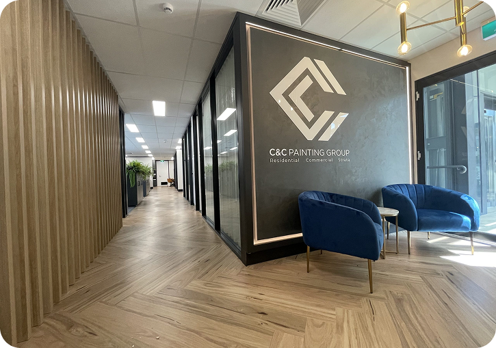 C&C Painting Group office interior featuring modern design, logo display, and blue chairs in a well-lit corridor, reflecting professionalism and quality service.