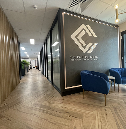 C&C Painting Group office interior featuring modern design elements, logo on wall, and stylish blue chairs, reflecting professionalism in residential and commercial painting services.