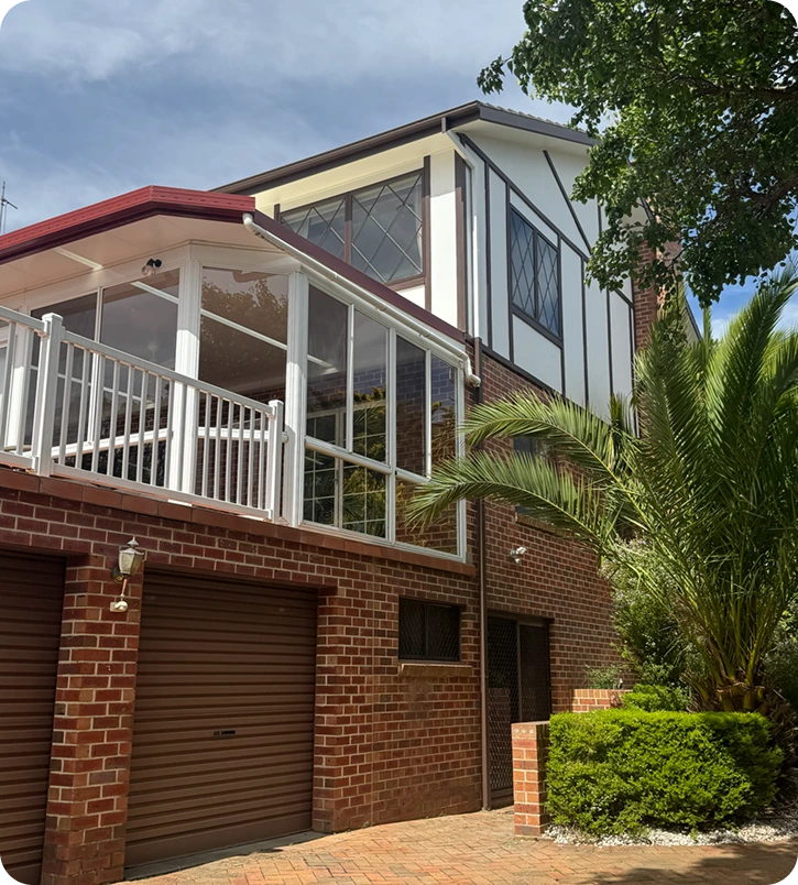 Residential home exterior featuring modern architectural design, brick facade, and a glass-enclosed balcony, highlighting C&C Painting Group's expertise in enhancing home aesthetics and protection through professional repainting services.