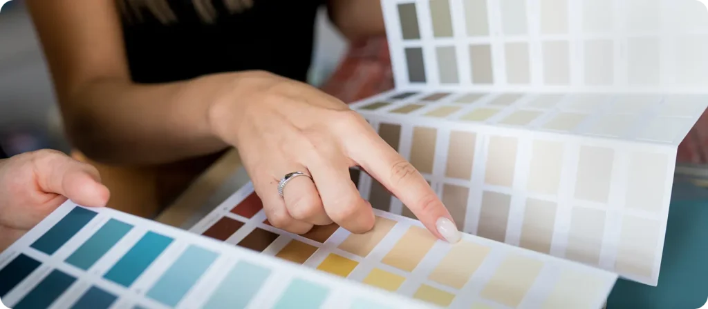 Person selecting paint colours from a palette, showcasing a range of hues for home transformation projects with C&C Painting Group in Canberra.