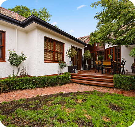 Residential property exterior with landscaped garden, wooden deck, and dining area, showcasing C&C Painting Group's home repaint services in Canberra.