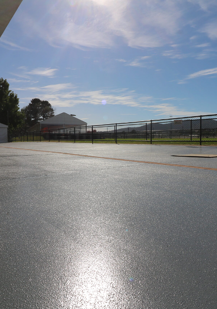 Decorative concrete resurfacing at Thoroughbred Park, Canberra, showcasing a smooth, modern finish with sunlight reflecting off the surface, surrounded by fencing and greenery.