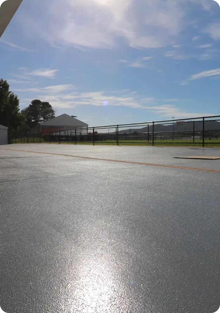 Decorative concrete resurfacing at Thoroughbred Park, showcasing a smooth, modern finish under sunlight, with clear blue skies and surrounding structures in the background.