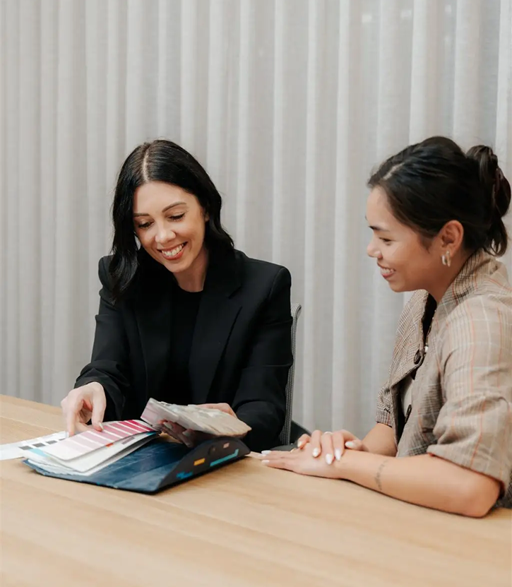 Two women discussing paint colour samples in a professional setting, showcasing C&C Painting Group's commitment to customer engagement and personalised service.