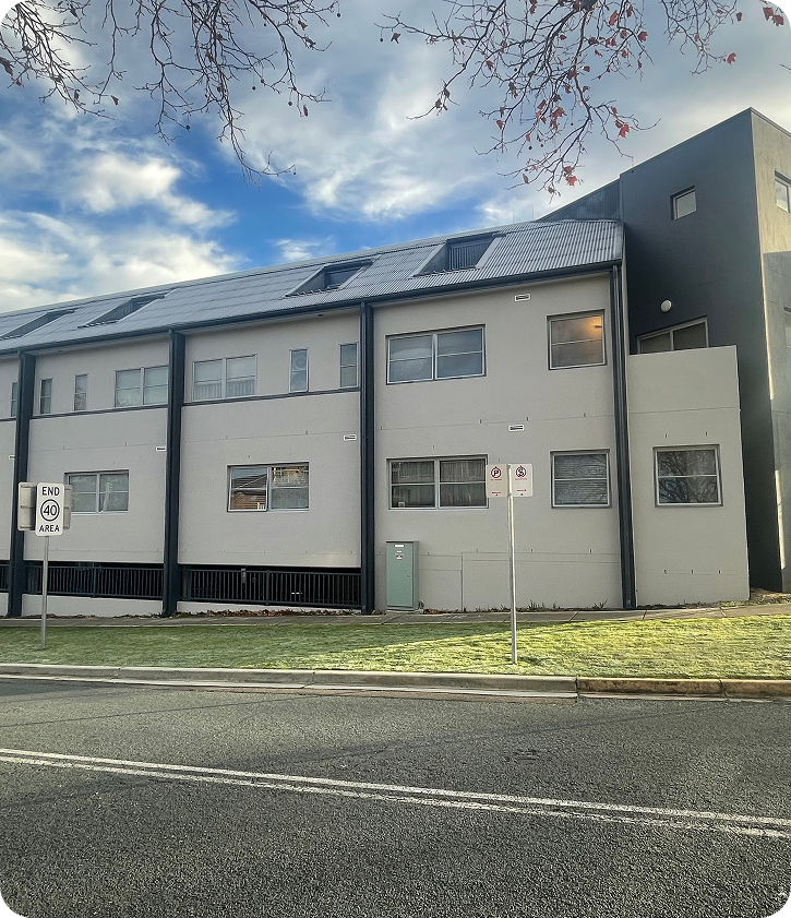 Strata residential building showcasing modern architecture, grey exterior, and clear signage, representing C&C Painting Group's high-quality painting services for strata and body corporate properties in Canberra.