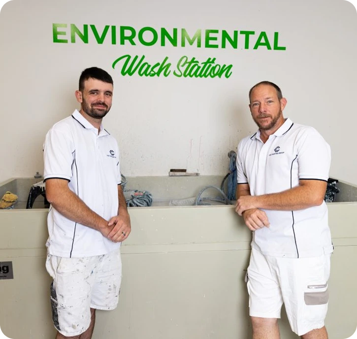 Two professional painters standing beside an environmentally responsible wash station, showcasing C&C Painting Group's commitment to sustainable practices in Canberra.