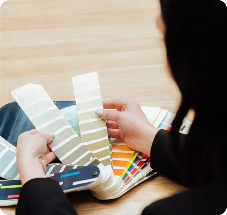 Person selecting paint samples from a colour swatch booklet, showcasing a variety of hues for home repainting, reflecting C&C Painting Group's commitment to quality and customer satisfaction.