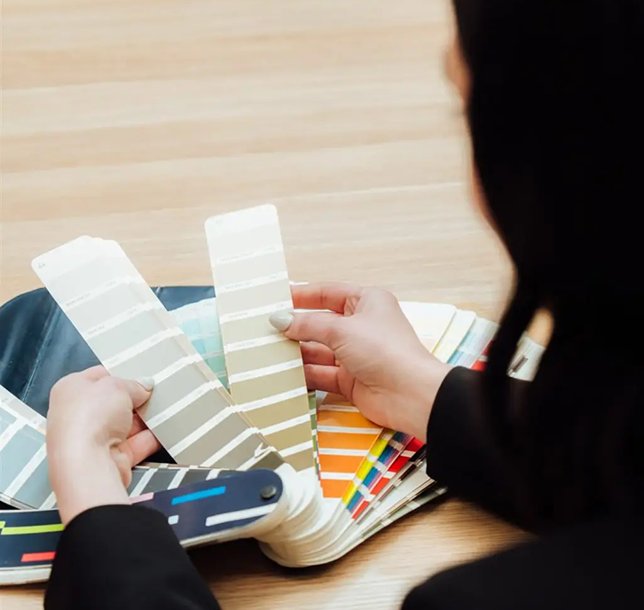 Person selecting paint colour samples from a fan deck, showcasing a variety of shades for home repainting projects.