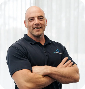 Co-owner of C&C Painting Group, smiling confidently with arms crossed, showcasing commitment to quality and customer service in a professional setting.