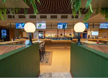 Modern bar interior with green accents, stylish lighting, and multiple screens displaying information, showcasing a professional and inviting atmosphere for commercial and government events.