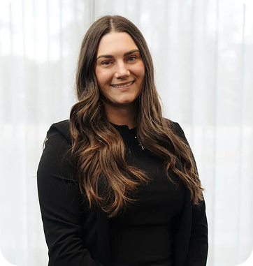 Headshot of a woman with long, wavy hair, wearing a black blazer, smiling in front of a light background, representing C&C Painting Group's team member.