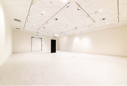 Empty commercial interior space with modern design, featuring white walls, a textured ceiling, and a black partition, suitable for painting projects and renovations by C&C Painting Group.