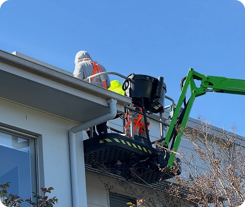 Workers using a cherry picker for building maintenance and painting services on a strata property in Canberra.