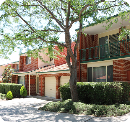 Residential building exterior with brick façade, landscaped garden, and driveway, representing C&C Painting Group's home repaint services in Canberra.