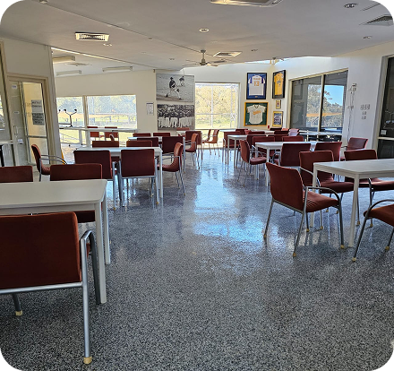 Interior of a spacious dining area featuring tables and chairs, showcasing decorative concrete resurfacing with a glossy finish, suitable for commercial and government settings.
