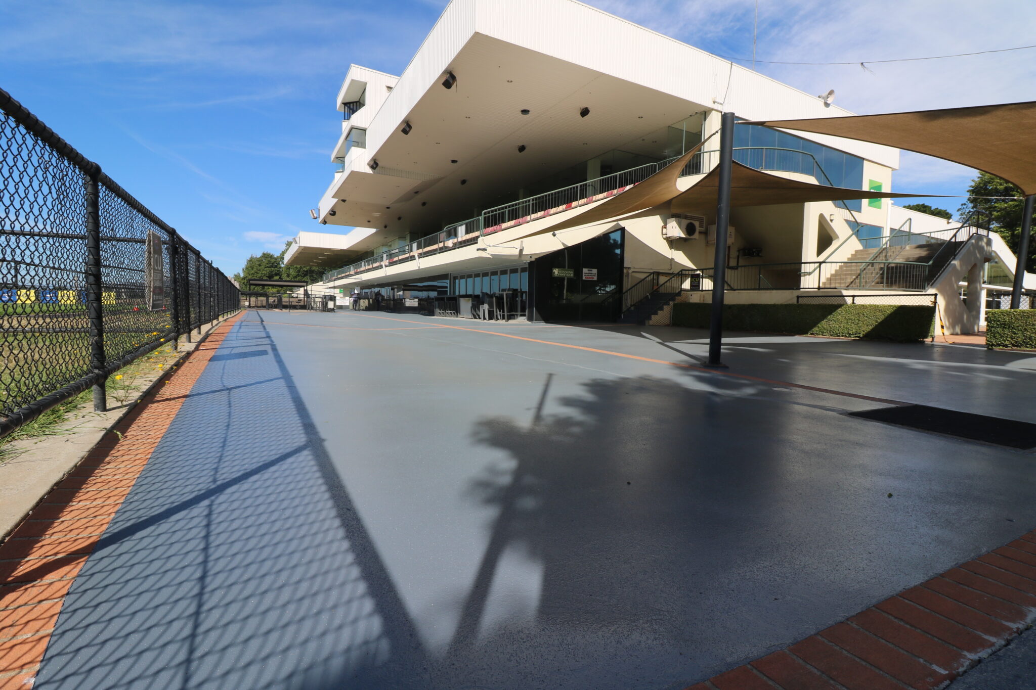Exterior concrete resurfacing at Thoroughbred Park, featuring a smooth grey surface and modern architectural elements of the building in the background.