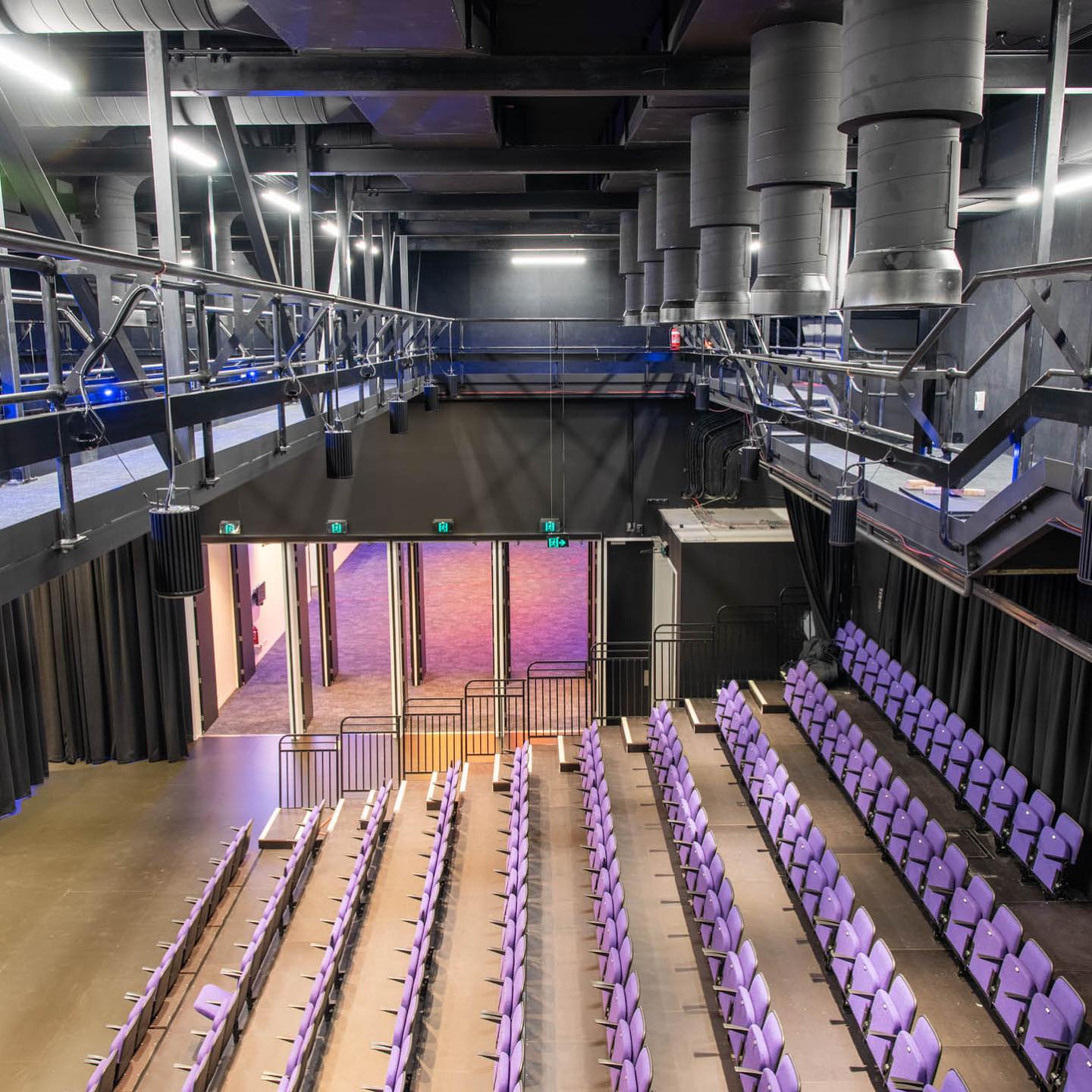 Interior view of the Belconnen Art Centre auditorium featuring rows of purple seating, overhead lighting, and a modern industrial design, showcasing C&C Painting Group's commercial painting work.