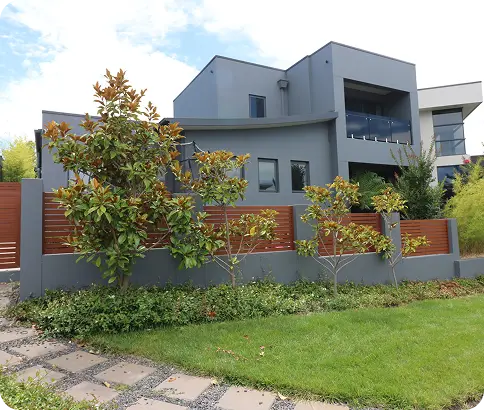 Modern home exterior in Canberra with grey walls, landscaped garden, and decorative trees, showcasing a professional repainting service by C&C Painting Group.
