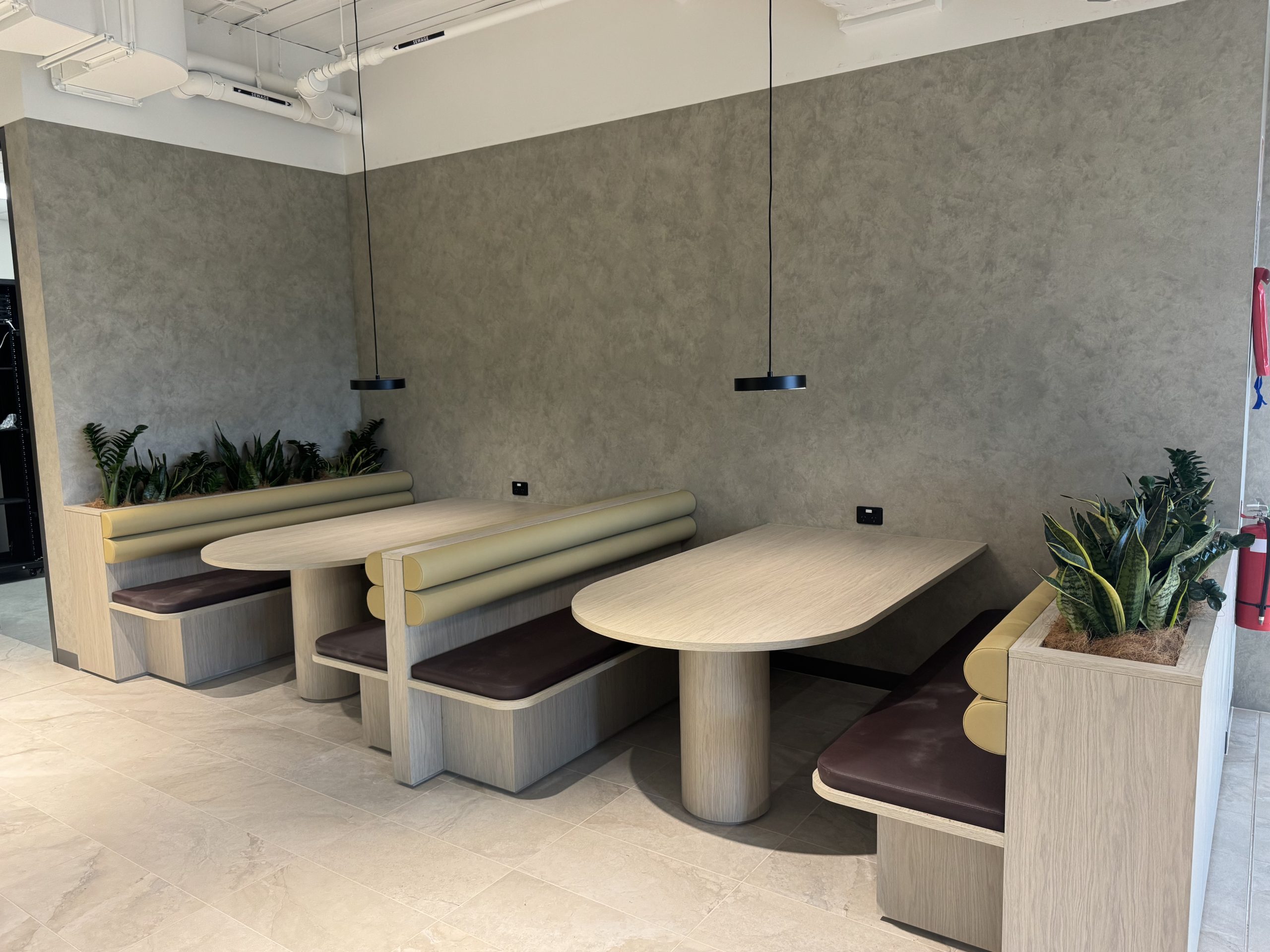 Modern seating area at Canberra Southern Cross Club featuring stylish booths with wooden finishes, plush cushions, and decorative plants, showcasing C&C Painting Group's repainting services.