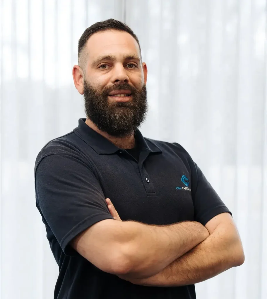 Warren Stefszky, Customer Sales Advisor at C&C Painting Group, smiling with arms crossed, showcasing professionalism and approachability in a bright setting.