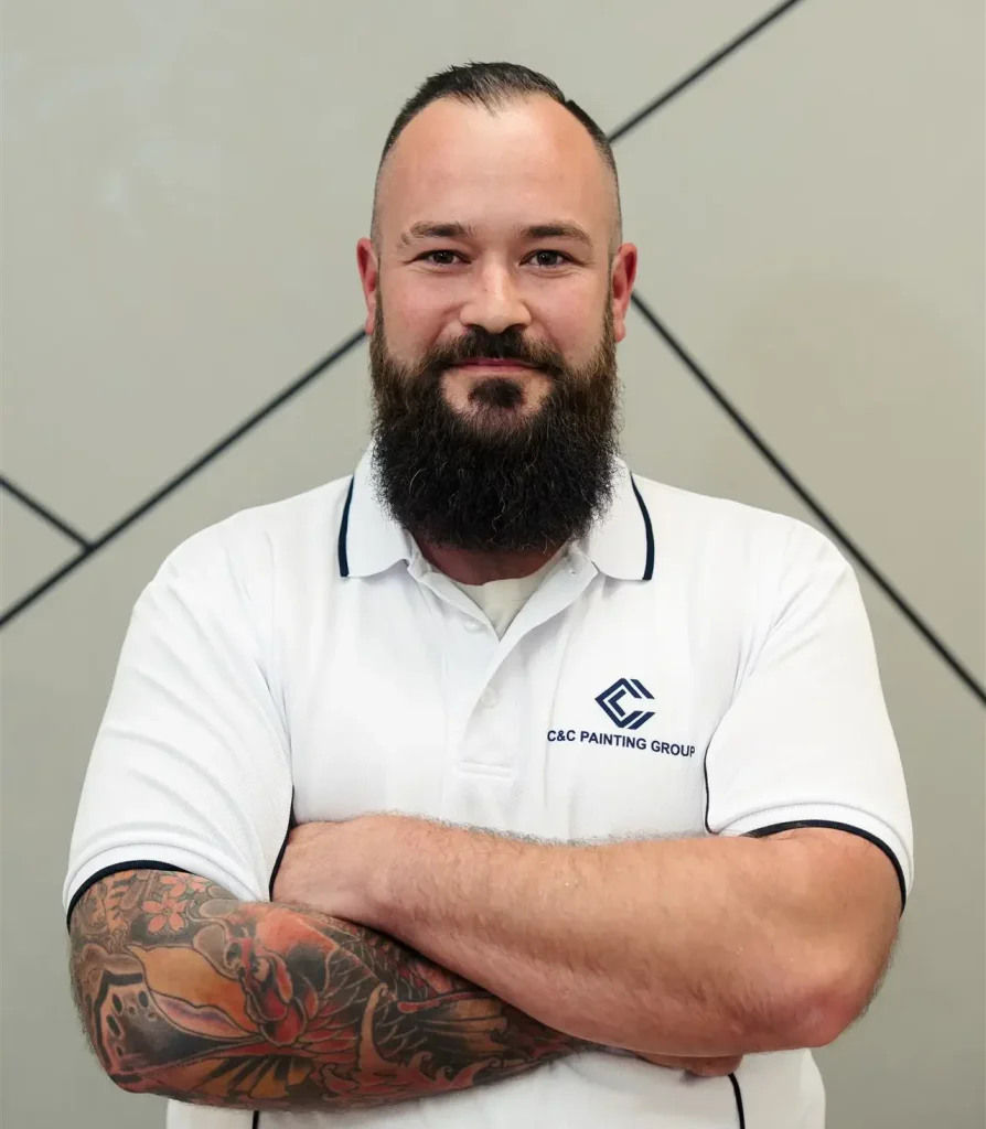 Matthew Singh, Team Leader at C&C Painting Group, smiling with arms crossed, wearing a branded polo shirt, showcasing professional expertise in painting services.